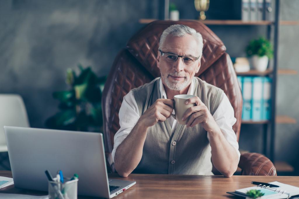 Goed Werkgeverschap - man met koffie kijkt op zijn laptop