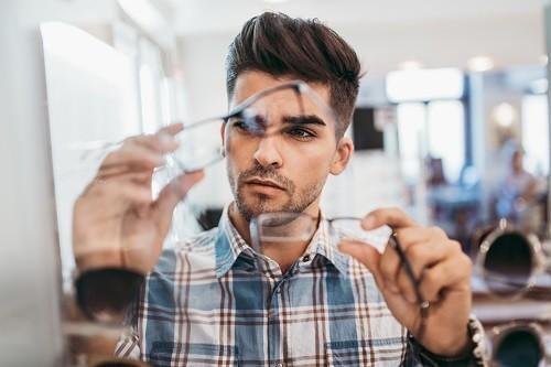 Opticiens en audiciens - man vergelijkt twee brillen