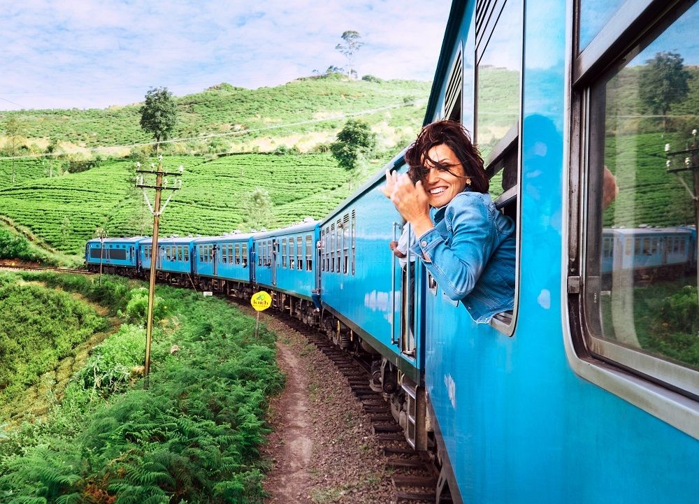 COVID-19 en uw reisverzekering - zwaaiende vrouw uit trein in groen landschap