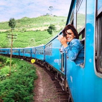 COVID-19 en uw reisverzekering - zwaaiende vrouw uit trein in groen landschap